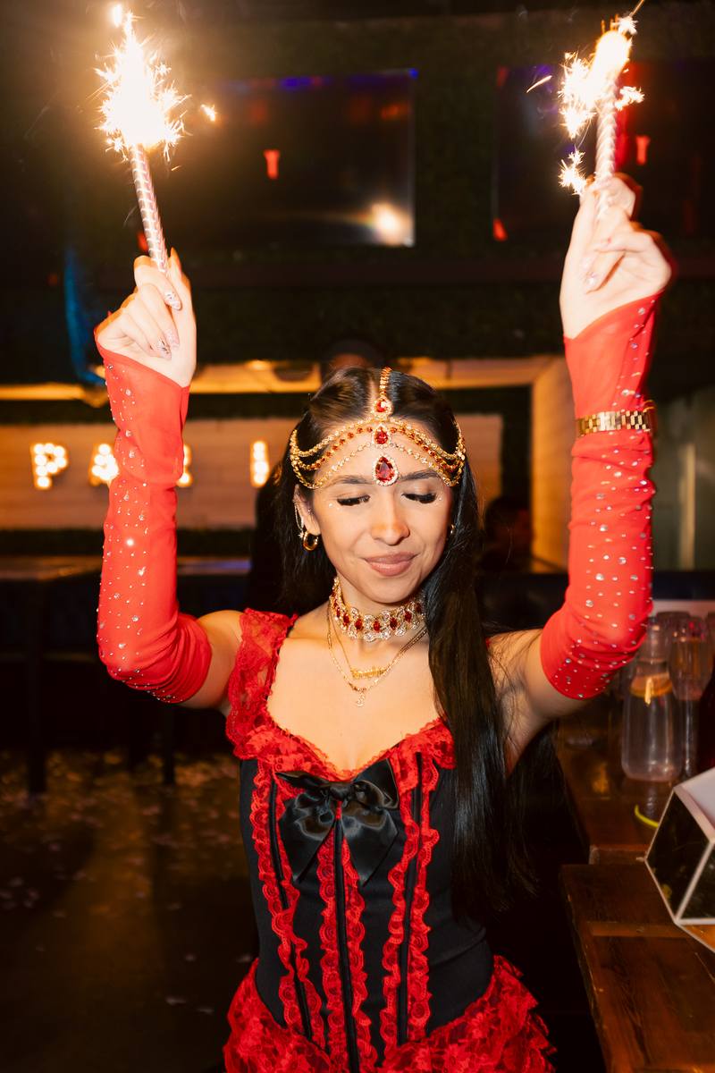 An attendee holding sparklers in costume at a Crawlloween venue