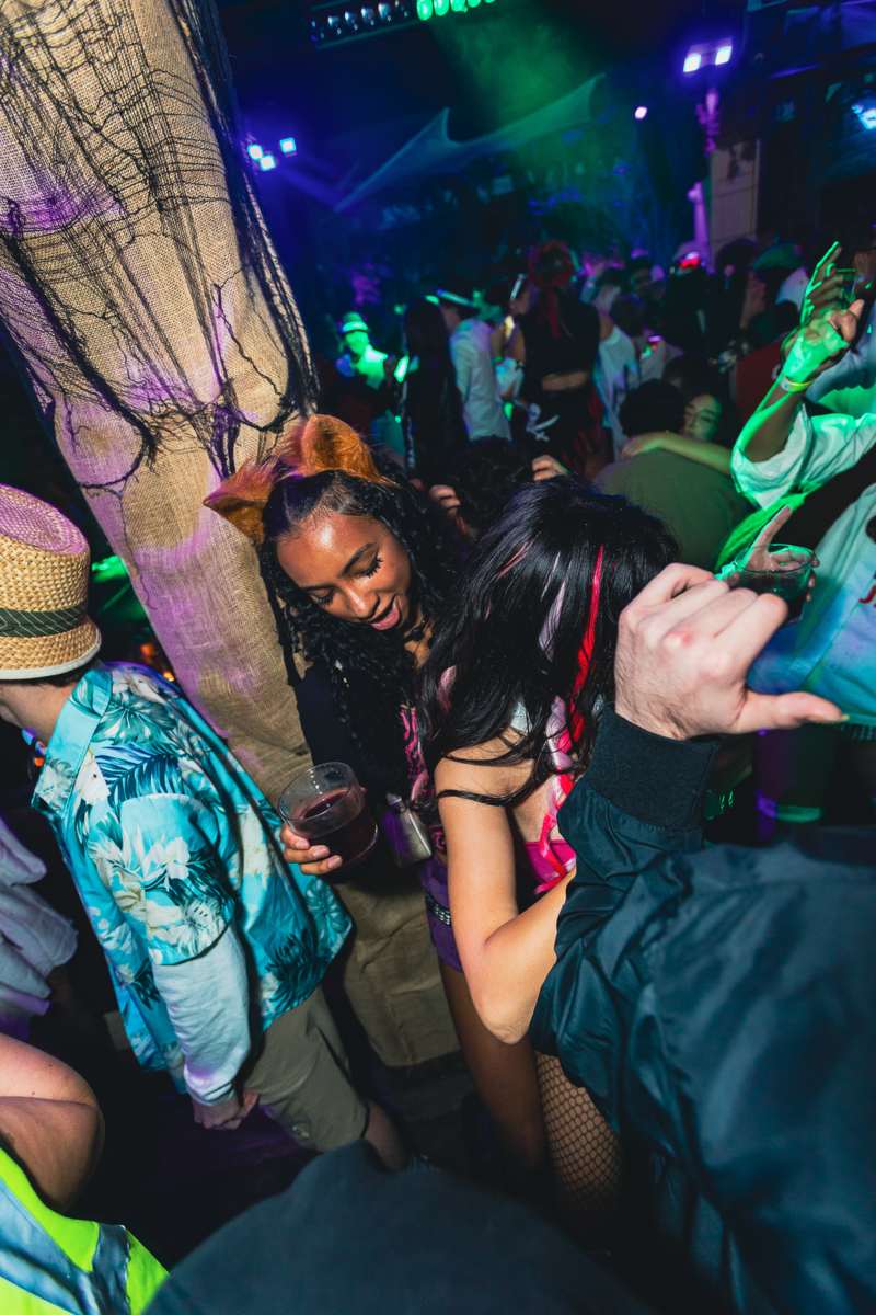 Crawlers dancing under club lighting on Halloween night