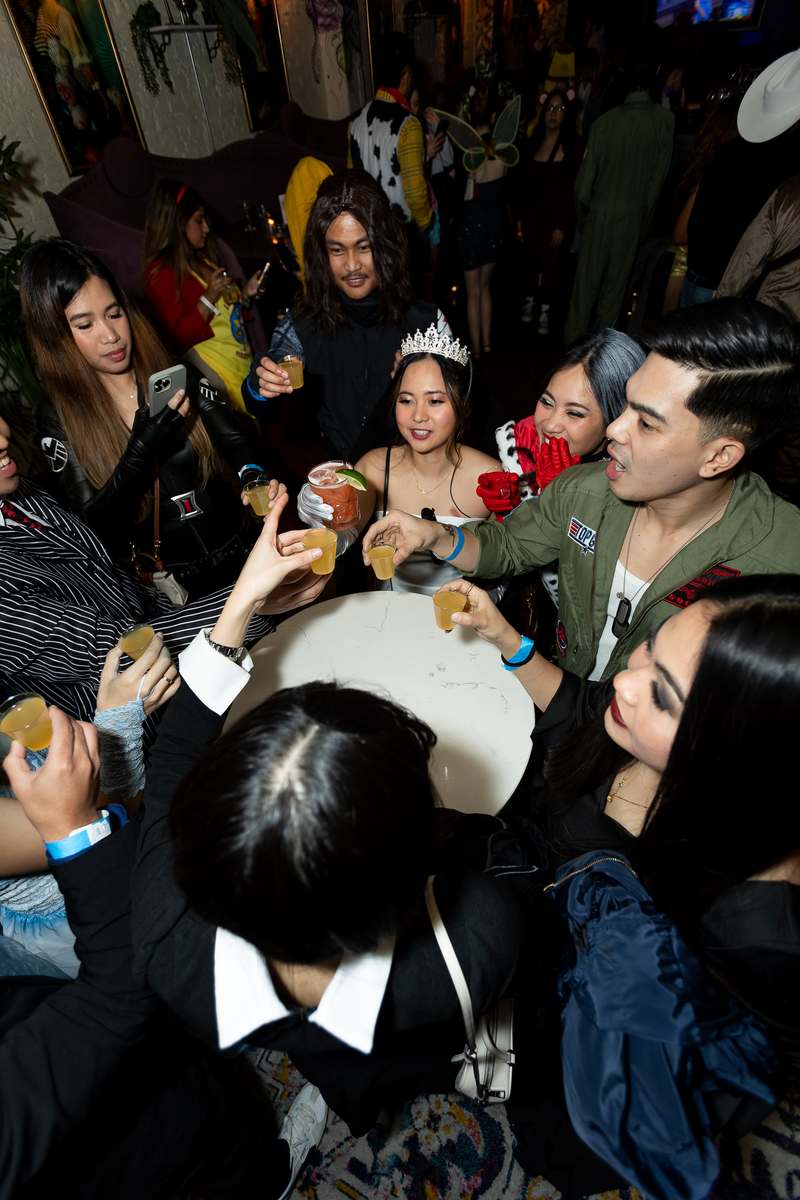 A table of friends raising drinks together during Crawlloween