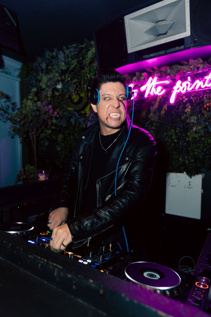A DJ behind the decks at Point and Feather during Crawlloween