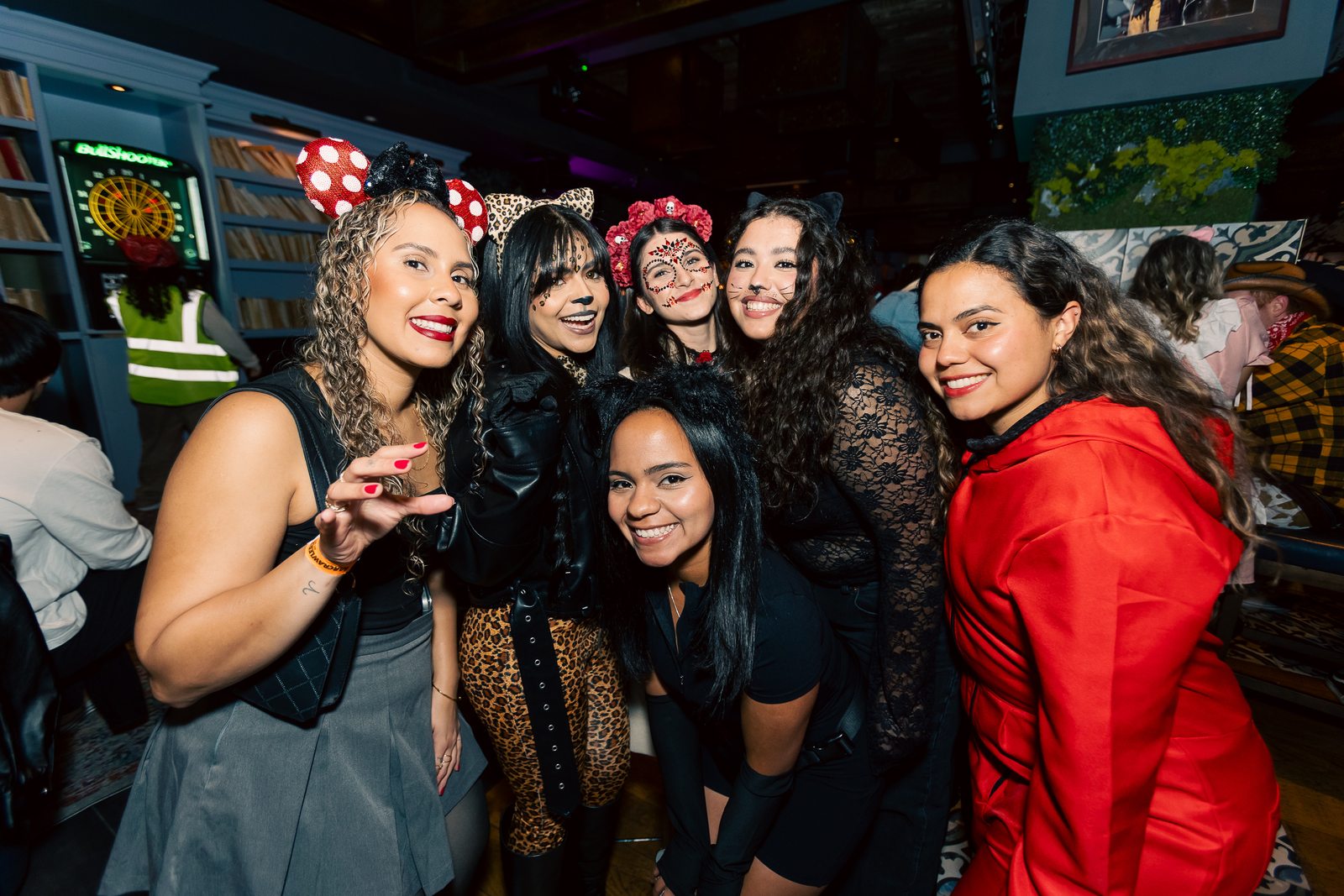 A costumed group posing in front of arcade screens at a Crawlloween stop