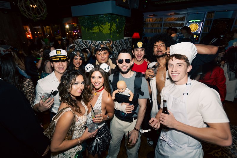 A large group in costume crowded together inside a River North bar on Halloween night