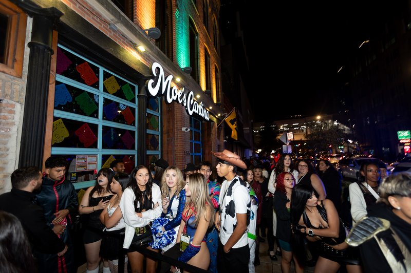 Costumed crawlers filling the sidewalk outside Moe's Cantina on West Kinzie during Crawlloween 2025